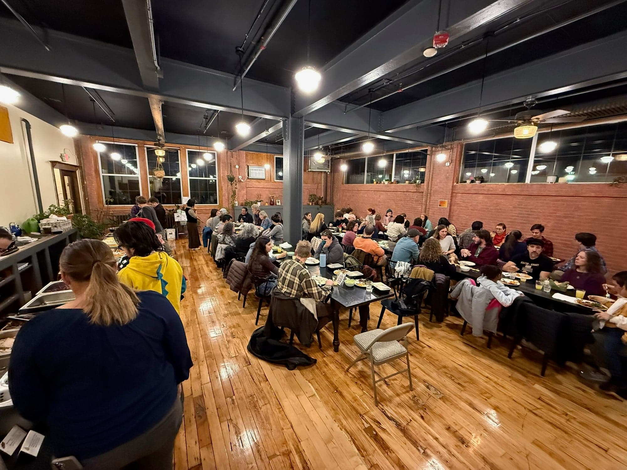 The whole community sharing a meal at the long tables in the LightHouse dining hall